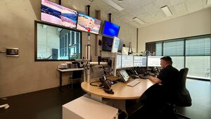 Bild vergr&ouml;&szlig;ern: Feuerwehreinsatzzentrale der Berufsfeuerwehr mit mehreren Bildschirmen in der ein Mitarbeiter der Berufsfeuerwehr sitzt.