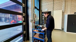 Bild vergr&ouml;&szlig;ern: Ein Mitarbeiter der Berufsfeuerwehr der auf einem Rollwagen Elektrogeräte prüft.