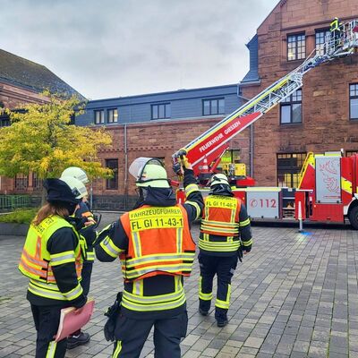 Bild vergr&ouml;&szlig;ern: Im Hintergrund die Drehleiter der Berufsfeuerwehr bei einer Übung am Bahnhof in Gießen,im Vordergrund Einsatzkräfte Berufsfeuerwehr und Freiwillige Feuerwehr.