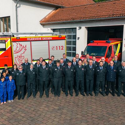 Bild vergr&ouml;&szlig;ern: Gruppenbild Freiwillige Feuerwehr Rödgen vor dem Gerätehaus mit Einsatzfahrzeugen.