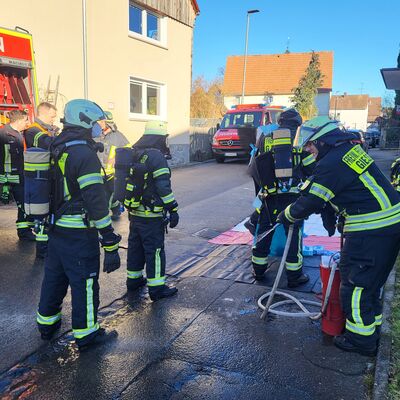 Bild vergr&ouml;&szlig;ern: Einsatzkräfte, zum Teil unter Atemschutz, vor einem Löschfahrzeug
