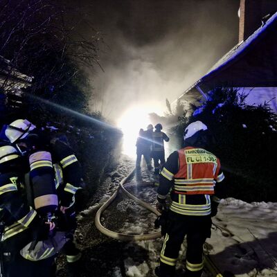 Bild vergr&ouml;&szlig;ern: Einsatzkräfte vor einem Gebäude, aus dem dichter Rauch dringt.