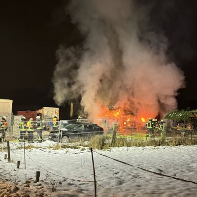 Bild vergr&ouml;&szlig;ern: Feuerschein in der Ferne sichtbar, davor Einsatzkräfte.