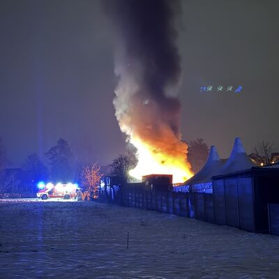Bild vergr&ouml;&szlig;ern: Feuerschein und Rauchentwicklung in der Ferne, daneben ein Löschfahrzeug