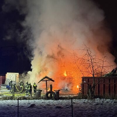 Bild vergr&ouml;&szlig;ern: Brennende Lastkraftwagen, daneben Einsatzkräfte im Löscheinsatz