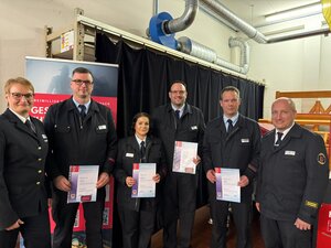 Sechs Einsatzkräfte in Uniform, vier davon mit Beförderungsurkunden