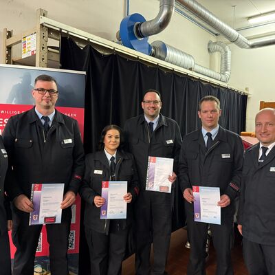 Bild vergr&ouml;&szlig;ern: Sechs Einsatzkräfte in Uniform, vier davon mit Beförderungsurkunden