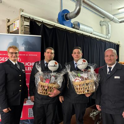 Bild vergr&ouml;&szlig;ern: Vier Einsatzkräfte in Uniform, zwei davon halten einen Präsentkorb.