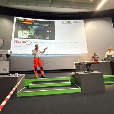 Bild vergr&ouml;&szlig;ern: Person auf einer Bühne vor einer Päsentationsleinwand