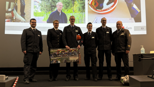 Einsatzkräfte mit Geschenken vor Leinwand