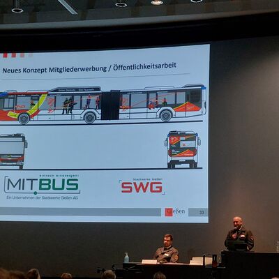 Bild vergr&ouml;&szlig;ern: Person vor Präsentation auf der ein Bus mit Feuerwehr Werbung gezeigt wird