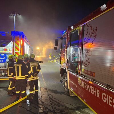 Bild vergr&ouml;&szlig;ern: Zwei Einsatzfahrzeuge und mehrere Einsatzkräfte vor einen rauchenden LKW-Auflieger