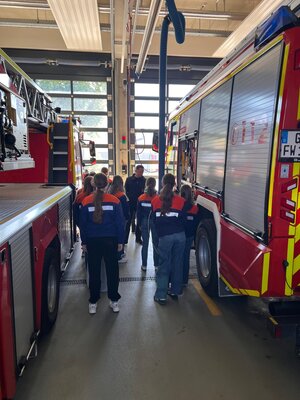 Mädchen in Jugendfeuerwehrbekleidung zwischen Einsatzfahrzeugen