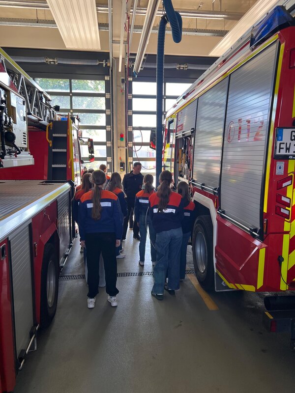 Mädchen in Jugendfeuerwehrbekleidung zwischen Einsatzfahrzeugen