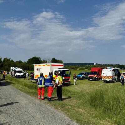 Bild vergr&ouml;&szlig;ern: Einsatzfahrzeuge und Einsatzkräfte auf einer Wiese.