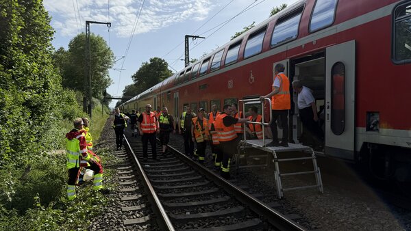 Einsatzkräfte mit einer Rettungsplattform vor einem Zug