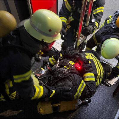 Bild vergr&ouml;&szlig;ern: Einsatzkräfte unter Atemschutz retten einen verunfallten Atemschutzgeräteträger