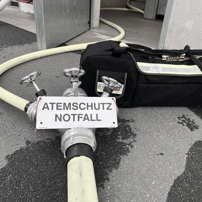 Bild vergr&ouml;&szlig;ern: Feuerwehrausrüstung vor einer Eingangstür, gekennzeichnet mit einem Schild Atemschutznotfall