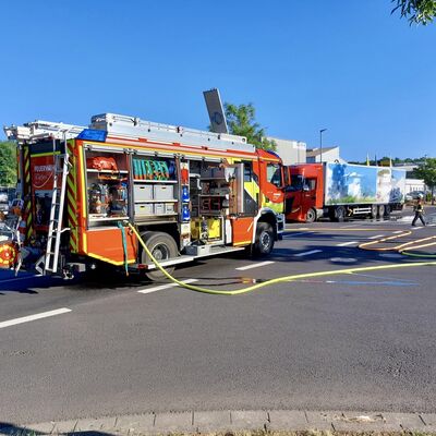 Bild vergr&ouml;&szlig;ern: Löschfahrzeug mit angeschlossenen Schläuchen, im Hintergrund ein LKW und Einsatzkräfte
