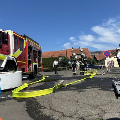 Bild vergr&ouml;&szlig;ern: Einsatzkräfte in Schutzausrüstung für einen Wettkampf neben einem Einsatzfahrzeug