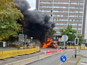 Brennender LKW vor einem Gebäude.