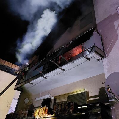 Bild vergr&ouml;&szlig;ern: Gebäude mit brennendem Balkon, es steigt Rauch auf.