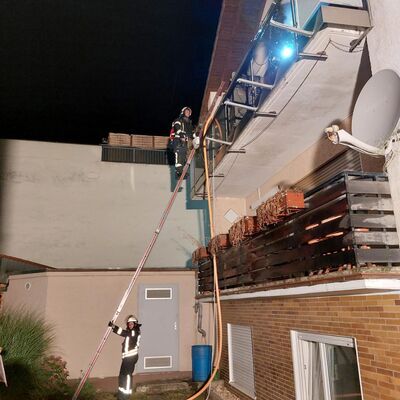Bild vergr&ouml;&szlig;ern: Einsatzkräfte besteigen einen Balkon über eine Leiter.