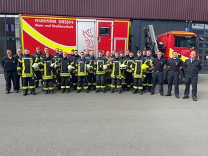 Einsatzkräfte in Brandschutzbekleidung vor einem Feuerwehrfahrzeug