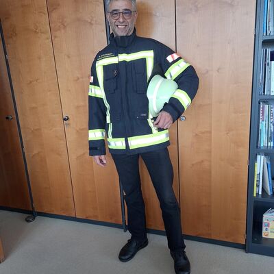 Bild vergr&ouml;&szlig;ern: Männliche Person mit Einsatzjacke und Feuerwehrhelm