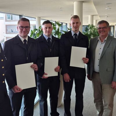 Bild vergr&ouml;&szlig;ern: Mehrere Personen in einem Flur, drei halten eine Urkunde in der Hand.