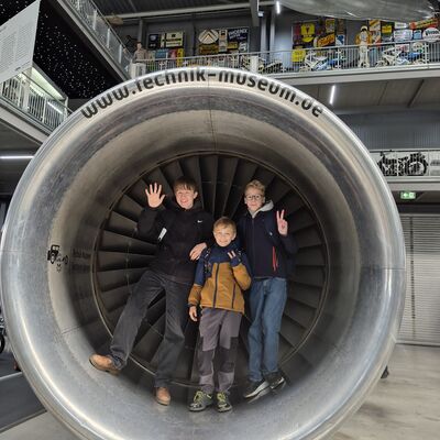 Bild vergr&ouml;&szlig;ern: Drei Jugendliche stehen in einer großen Turbine und grüßen in die Kamera