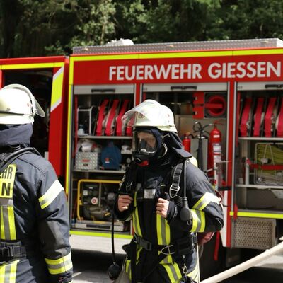 Bild vergr&ouml;&szlig;ern: Zwei Einsatzkräfte vor einem Löschfahrzeug