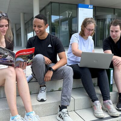 Bild vergr&ouml;&szlig;ern: Studierende vor Unigebäude
