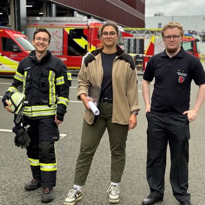 Bild vergr&ouml;&szlig;ern: Drei Einsatzkräfte vor Löschfahrzeugen